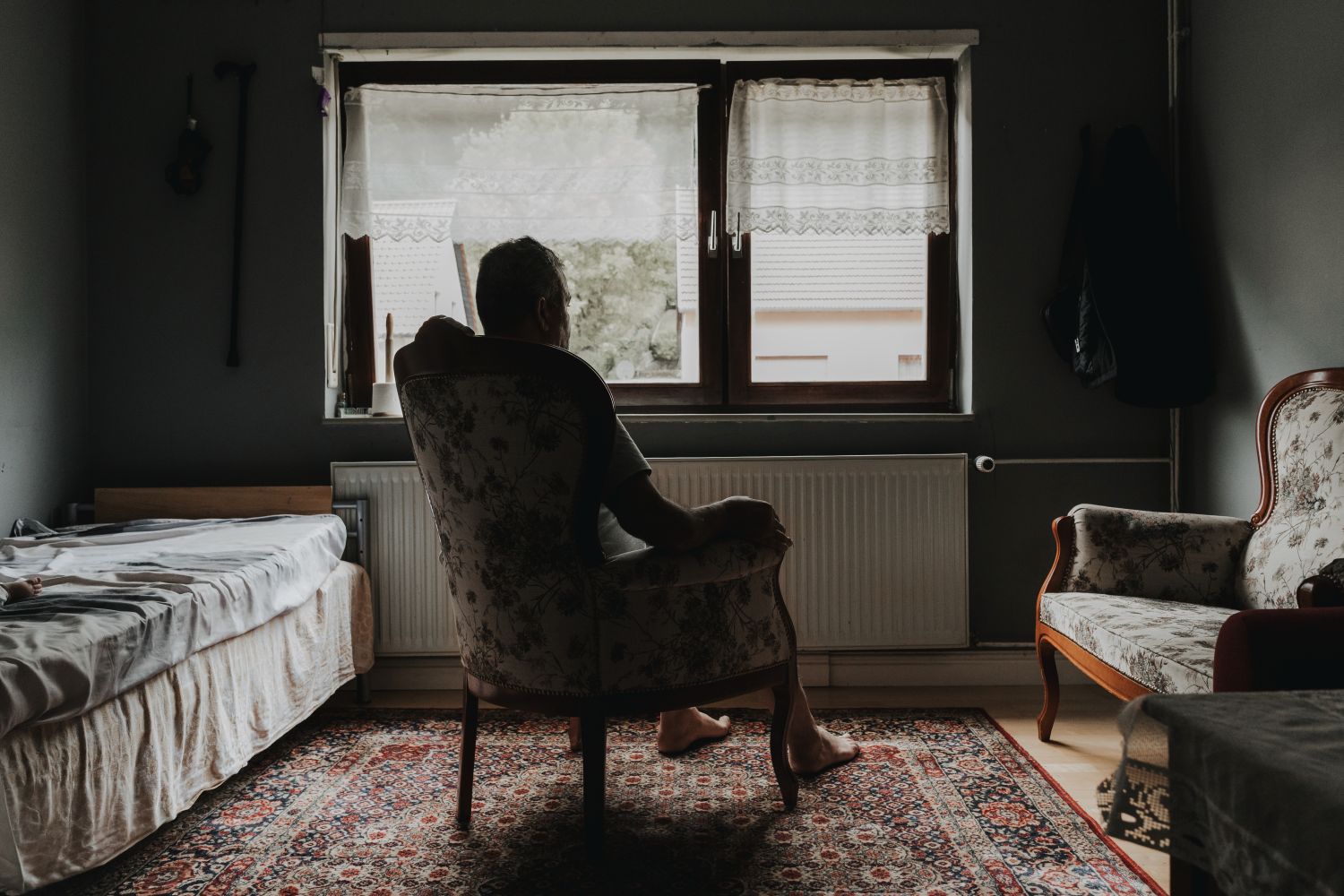 eine Person sitzt in einem dunklen Raum vor einem Fenster